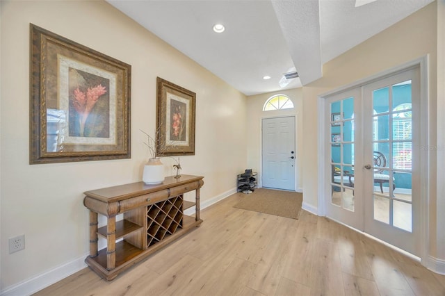 entrance foyer with a healthy amount of sunlight, french doors, baseboards, and light wood-style floors