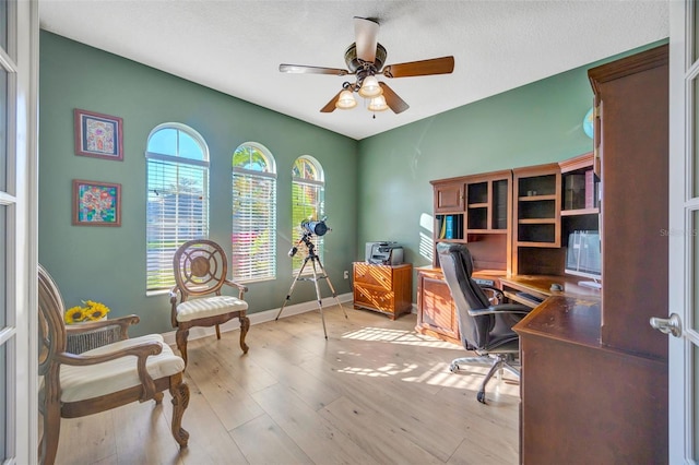 office space featuring baseboards, light wood-type flooring, and ceiling fan