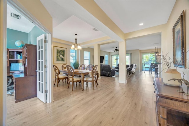 dining area with light wood finished floors, visible vents, ceiling fan with notable chandelier, and french doors