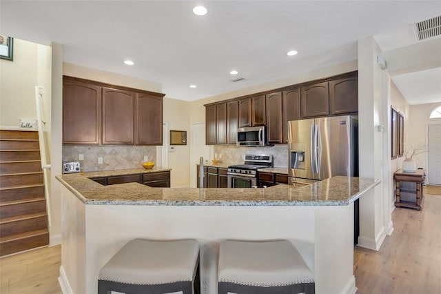 kitchen featuring light stone counters, visible vents, light wood finished floors, and stainless steel appliances