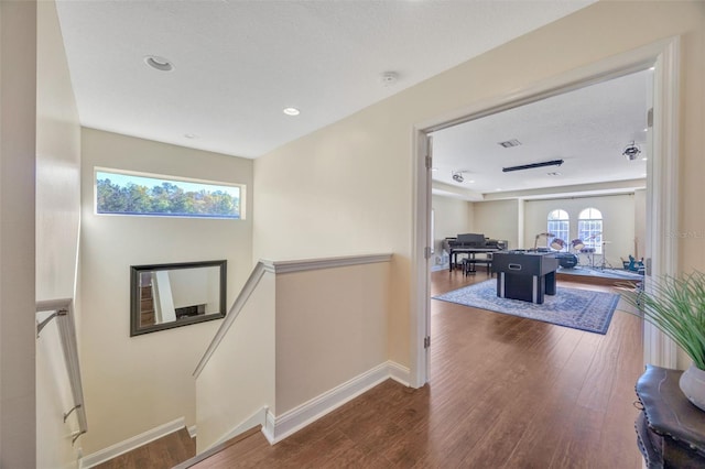 corridor featuring baseboards, an upstairs landing, visible vents, and wood finished floors