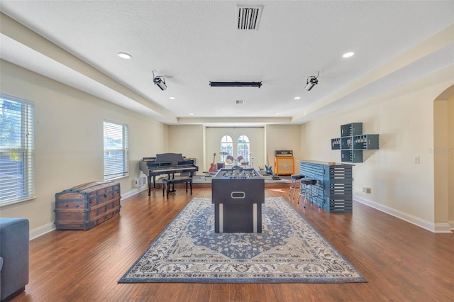 game room with dark wood-style floors, visible vents, arched walkways, and baseboards