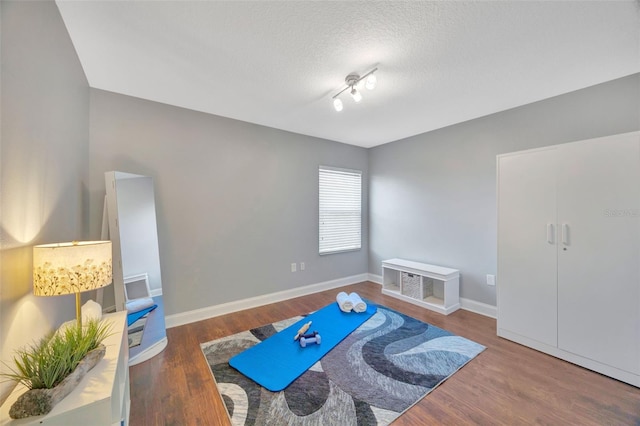 workout room with wood finished floors, baseboards, and a textured ceiling