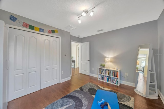 rec room featuring baseboards, wood finished floors, visible vents, and a textured ceiling