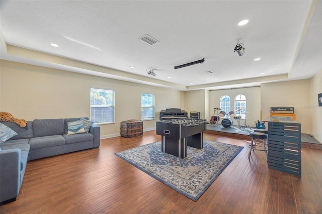 rec room featuring visible vents, a raised ceiling, dark wood-style floors, recessed lighting, and baseboards