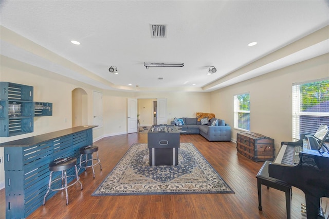 living area featuring visible vents, arched walkways, baseboards, and dark wood-style flooring