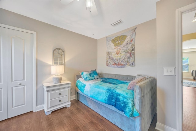 bedroom with ceiling fan, wood finished floors, visible vents, and baseboards