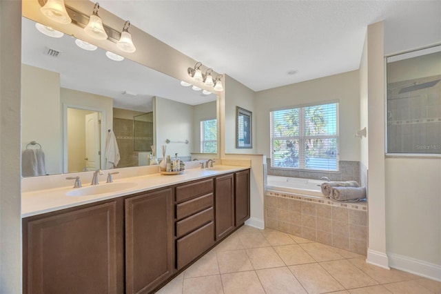 bathroom featuring tile patterned floors, visible vents, a tile shower, and a sink