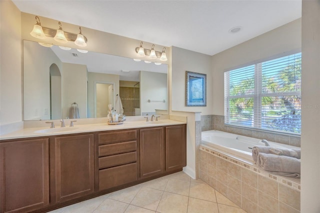 full bath featuring a sink, a garden tub, double vanity, and tile patterned floors