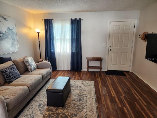 living room with a textured ceiling, baseboards, and wood finished floors