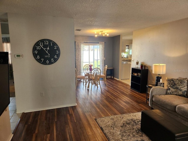 living room featuring a textured ceiling, baseboards, and wood finished floors