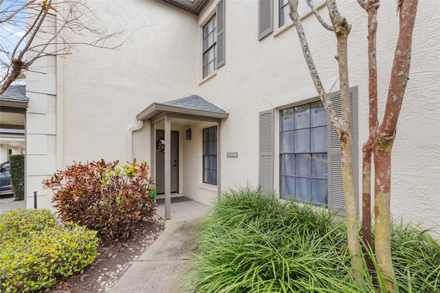 doorway to property with roof with shingles and stucco siding