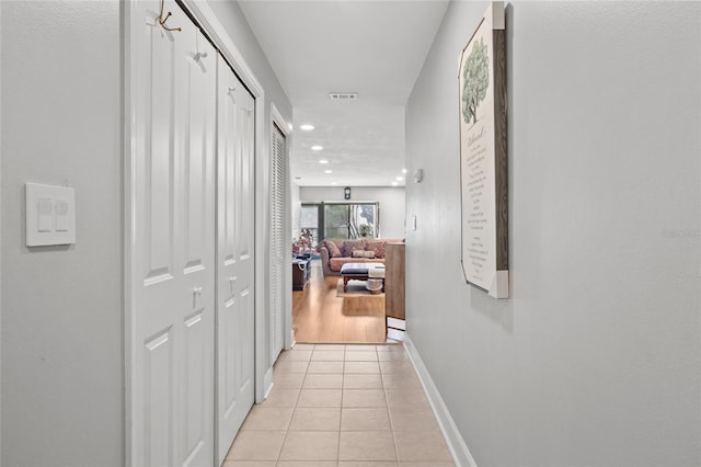 hall featuring light tile patterned floors, baseboards, visible vents, and recessed lighting