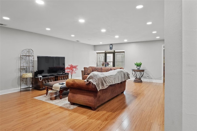 living room featuring light wood finished floors, baseboards, and recessed lighting