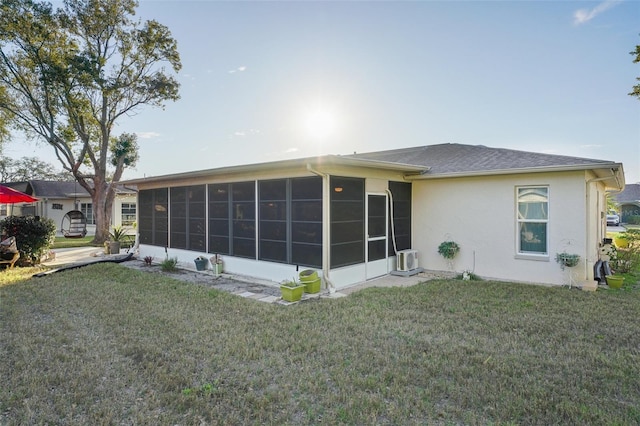 rear view of house featuring a sunroom, a yard, and stucco siding