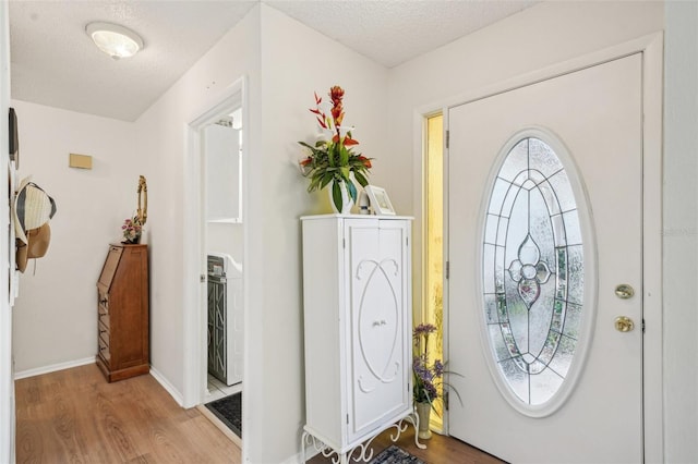 entryway featuring a textured ceiling, wood finished floors, and baseboards