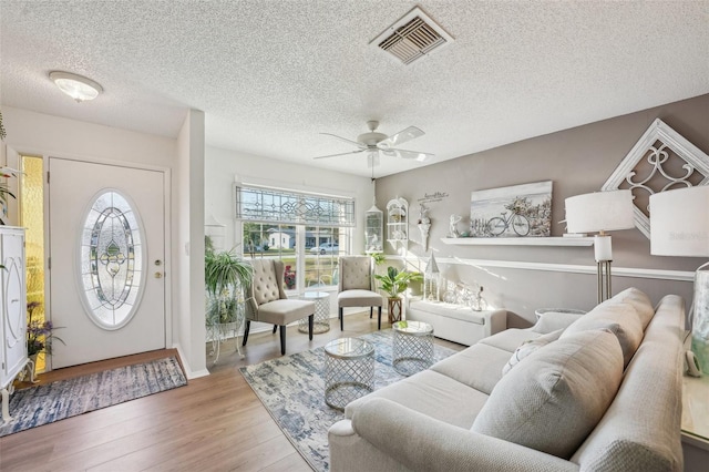 interior space featuring ceiling fan, a textured ceiling, wood finished floors, and visible vents