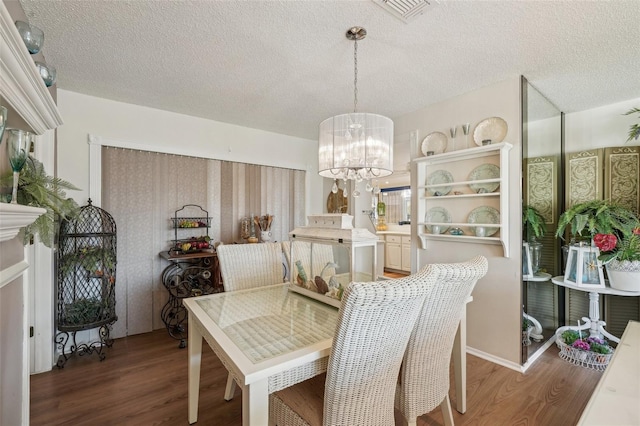 dining area featuring a chandelier, visible vents, a textured ceiling, and wood finished floors