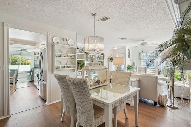 dining area featuring visible vents, wood finished floors, and ceiling fan with notable chandelier