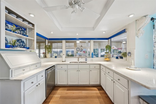 kitchen featuring light wood finished floors, white cabinets, a raised ceiling, dishwasher, and a sink