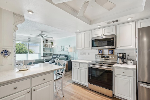 kitchen featuring ceiling fan, stainless steel appliances, visible vents, light wood-style floors, and crown molding