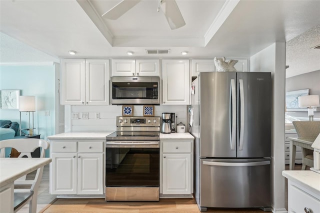 kitchen with stainless steel appliances, a tray ceiling, white cabinets, and visible vents