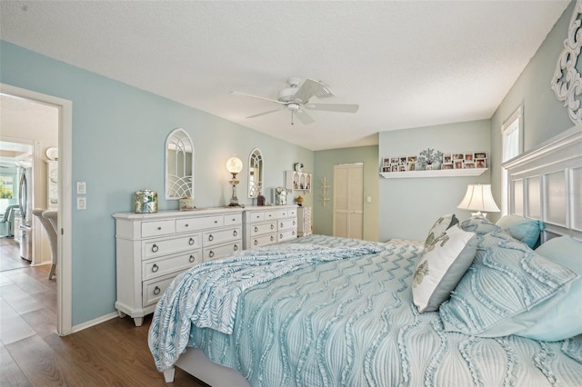 bedroom with dark wood-style floors, a textured ceiling, baseboards, and a ceiling fan