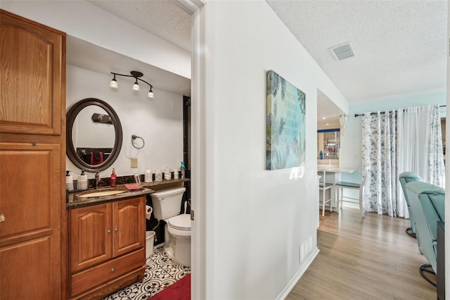 bathroom featuring visible vents, a textured ceiling, wood finished floors, and toilet