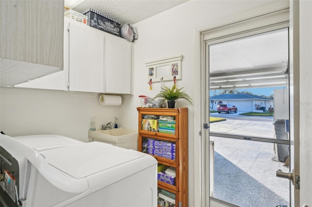 clothes washing area featuring cabinet space, independent washer and dryer, a textured ceiling, and a sink