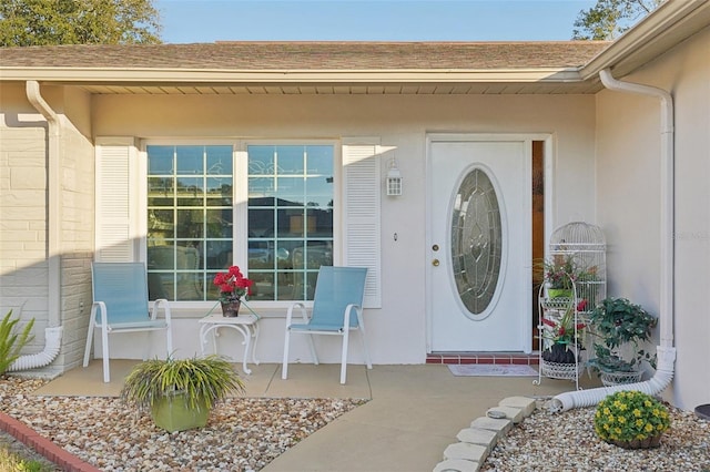 property entrance with a shingled roof and stucco siding