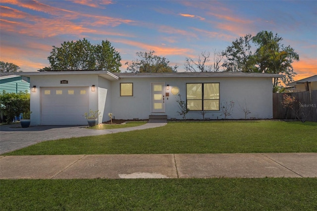 view of front facade featuring a garage, driveway, a lawn, and stucco siding