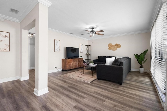 living room with a ceiling fan, visible vents, ornamental molding, and wood finished floors