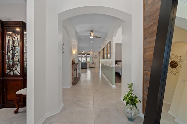 hallway featuring arched walkways and baseboards