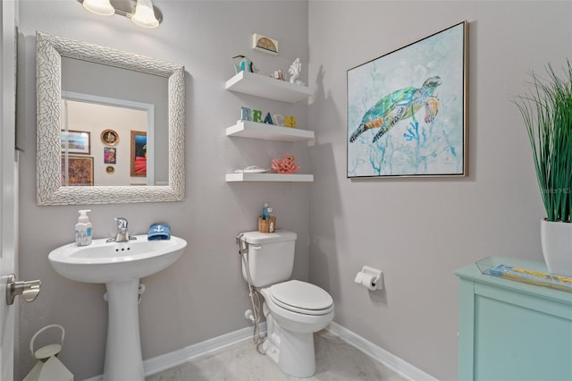 half bathroom with baseboards, a sink, and toilet