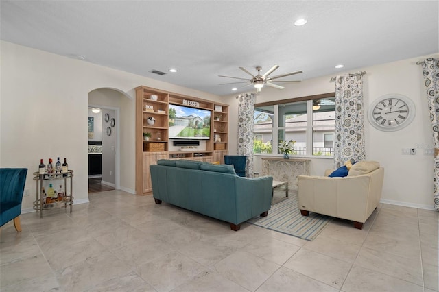 living area featuring arched walkways, recessed lighting, visible vents, and baseboards