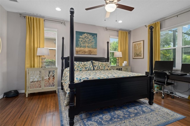 bedroom with a ceiling fan, visible vents, baseboards, and wood finished floors