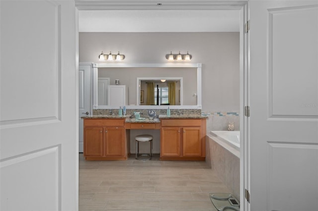 full bathroom featuring wood finished floors, double vanity, and a bath