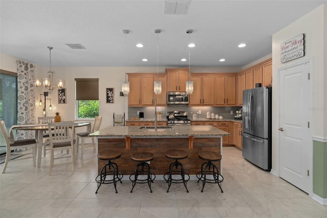 kitchen with a breakfast bar area, stone countertops, a sink, visible vents, and appliances with stainless steel finishes