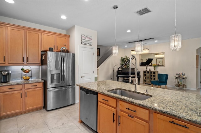 kitchen with visible vents, appliances with stainless steel finishes, brown cabinetry, and a sink