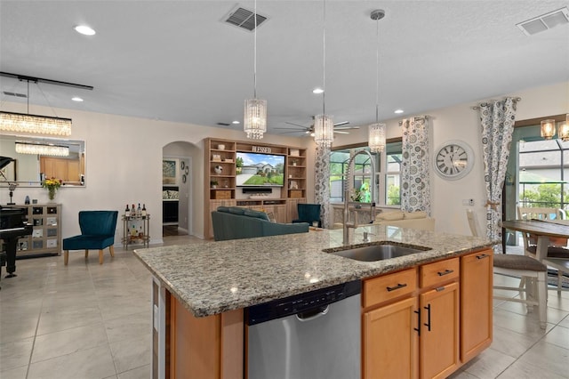 kitchen featuring arched walkways, a sink, visible vents, stainless steel dishwasher, and a center island with sink