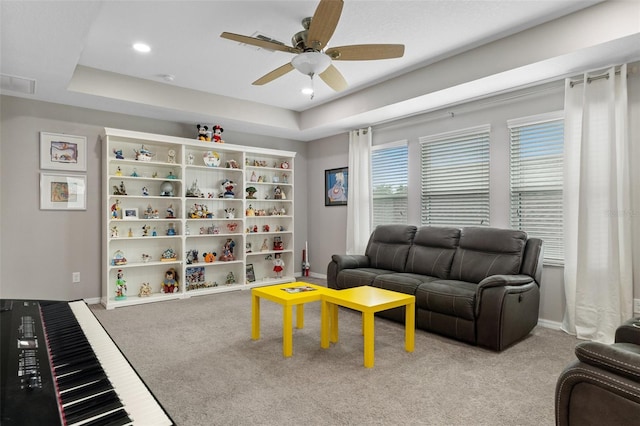 living room featuring baseboards, visible vents, a raised ceiling, a ceiling fan, and carpet floors