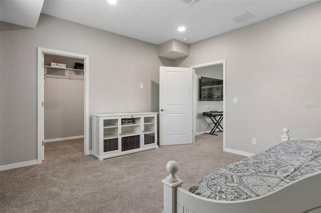 bedroom featuring carpet, a walk in closet, visible vents, and baseboards