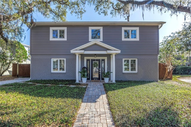 traditional home featuring a front yard, fence, and brick siding