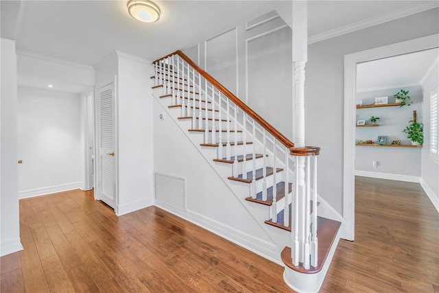 staircase with ornamental molding, wood finished floors, visible vents, and baseboards