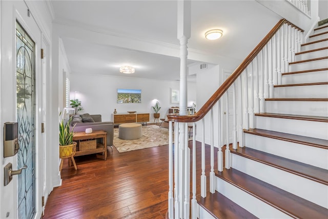 stairway with visible vents, crown molding, and hardwood / wood-style floors