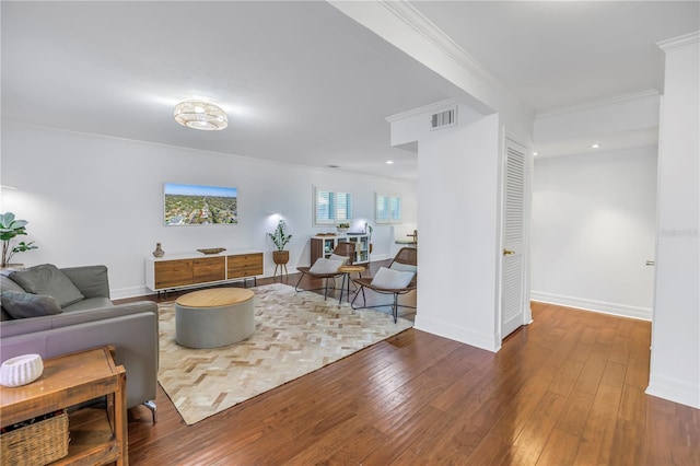 living area with baseboards, crown molding, visible vents, and hardwood / wood-style floors