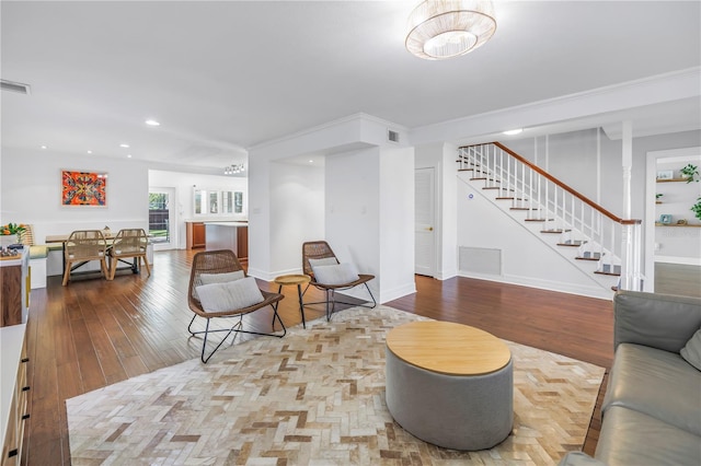 living room with stairs, visible vents, baseboards, and hardwood / wood-style flooring