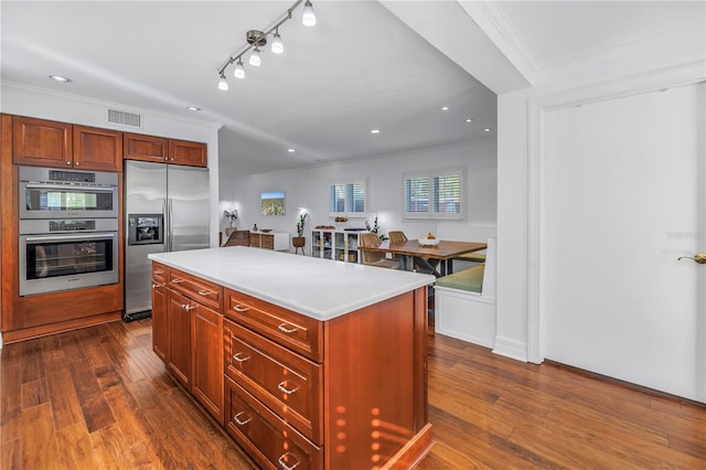 kitchen featuring visible vents, dark wood-style floors, appliances with stainless steel finishes, light countertops, and crown molding