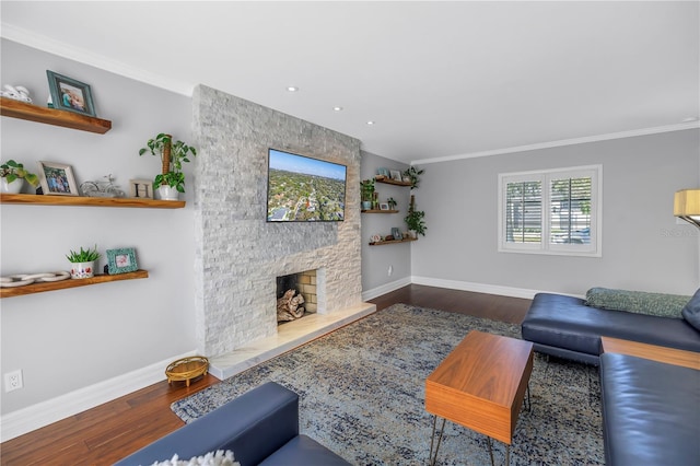 living room featuring ornamental molding, a stone fireplace, baseboards, and wood finished floors