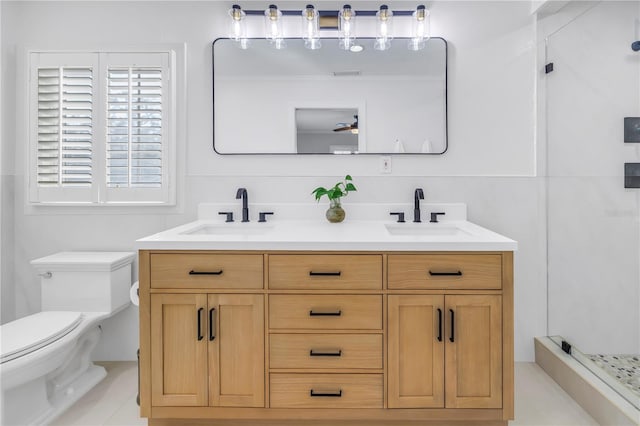 bathroom featuring toilet, a shower stall, double vanity, and a sink